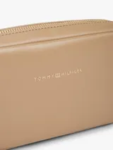 Cartera bandolera de poliuretano color beige, modelo Essential de Tommy Hilfiger, con diseño compacto de líneas redondeadas, cierre de cremallera e inscripción de la marca en bajo relieve en el frente. Cuenta con una correa cruzada ajustable de jacquard tonal.