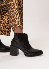 Botín negro de cuero con elástico lateral y cierre interno. Tiene plataforma delantera de 2 cm y taco de 8 cm.