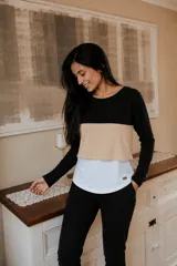 Remera de manga larga con diseño tricolor en bloques horizontales negro, beige y blanco. Presenta un corte holgado y funcional, ideal para maternidad y lactancia.