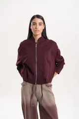 Campera bomber de paño color bordó, con cuello alto, cierre frontal metálico y mangas amplias con hombro caído. Presenta un calce relajado y silueta levemente corta con ajuste inferior.