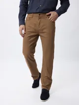 Pantalón de corte recto en color tostado, confeccionado en tejido de algodón con elastano. Presenta cierre frontal con botón y cremallera, además de bolsillos laterales y traseros.