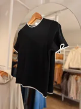 Remera tejida de manga corta con cuello redondo, confeccionada en una mezcla de poliéster, acrílico, poliamida y lana. Presenta un diseño de calce recto en color marrón con detalles de terminaciones en contraste de color blanco en el cuello, las mangas y el ruedo.