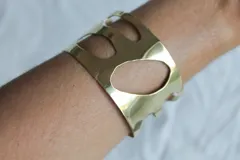 Brazalete rígido de bronce color dorado con diseño calado irregular.