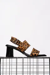 Sandalias con estampado animal print, con dos tiras anchas sobre el empeine y tira trasera con hebilla. El taco es cuadrado y de color negro brillante.