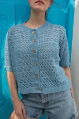 Saco tejido de punto calado con mangas al codo, cuello redondo y cierre frontal con botones de coco. Presenta un diseño versátil y ligero.