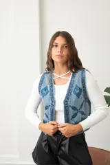 Chaleco de jean azul con bordados geométricos y detalles de lentejuelas a tono. Presenta un diseño sin mangas con cierre frontal y corte ajustado.