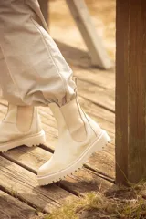 Bota de cuero color marrón con elásticos laterales negros, caña baja y suela negra artesanal de neolite.