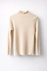 Media polera de tejido acanalado con interior de plush ultra suave. Presenta cuello alto, mangas largas y terminaciones con borde ondulado (lettuce edge) en cuello, puños y ruedo.