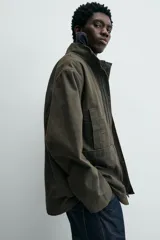 Parka de algodón con acabado lavado, color verde oscuro, de corte relajado. Presenta cuello subido, cierre frontal oculto por solapa con botones a presión, bolsillos de vivo en el pecho y bolsillos plastrón en la cadera.