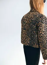 Chaqueta corta de corte recto con estampado de leopardo, cuello camisero, cierre frontal con botones y dos bolsillos de parche delanteros.