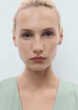 Vestido midi de color verde menta, con cuello en pico, mangas cortas y diseño evasé. Presenta costuras verticales decorativas a lo largo de la prenda y cierre de cremallera en la parte posterior.