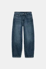 Jeans de tiro medio con corte tapered y largo al tobillo. Presenta un diseño de cinco bolsillos, cierre frontal con cremallera y botón, y un estampado de lunares a contraste sobre un tejido denim con efecto lavado.