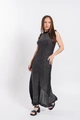 Vestido largo de tejido de punto con brillo, color negro con sutiles hilos metalizados, sin mangas, con cuello alto y aberturas laterales.