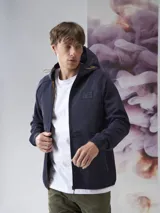 Campera azul marino con capucha, cierre frontal y bolsillos laterales con cierre. Tiene un parche con el logo de la marca en el pecho.