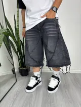 Pantalón baggy desmontable de denim gris oscuro con efecto lavado, diseño de paneles con costuras a la vista y terminaciones desflecadas.