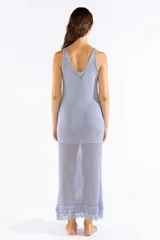 Vestido largo de punto abierto con brillo de lúrex y flecos en el ruedo, de corte recto, sin mangas y escote en V.