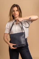 Bandolera de diseño simple con tapa frontal, confeccionada en material símil cuero. Cuenta con correa ajustable, división interna y bolsillos internos para mayor organización.