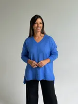 Sweater de tejido de punto color azul, con escote en V, manga larga con puños acanalados y diseño holgado con costura central vertical y ruedo asimétrico.