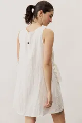 Vestido corto blanco sin mangas, con cuello redondo y detalle de nudo drapeado en el lateral.