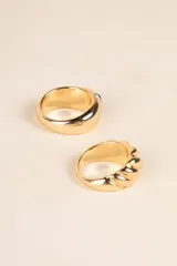 Set de dos anillos dorados. Uno con forma de cuerda trenzada y otro con una piedra amatista engarzada.