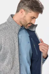 Chaleco de felpa gris con textura jaspeada, cuello alto y detalle de etiqueta de cuero sintético en la nuca.