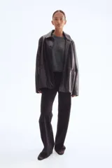 Buzo de punto fino color gris oscuro, con cuello redondo y manga corta. Presenta remates acanalados en cuello, puños y bajo.