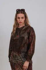 Campera bomber de cuero color marrón, con mangas abullonadas, puños elásticos y cierre frontal con botones a presión.