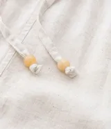 Pantalón de sarga color beige, modelo pantacourt (largo a media pantorrilla) con elástico y amarre en la cintura.