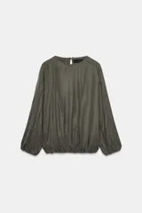 Blusa fluida de color verde oliva oscuro, con cuello redondo y mangas largas abullonadas. Presenta un diseño con bajo elástico y cierre posterior con abertura y botón.