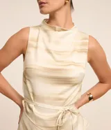 Blusa sin mangas de poliéster satinado con cuello alto y abertura en la espalda. Presenta un estampado abstracto en tonos beige y lazo en la cintura.