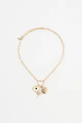 Collar de cadena de eslabones dorados con dije central en forma de corazón que sostiene tres colgantes: una luna creciente con una piedra negra, una estrella de ocho puntas con un cristal central y un disco circular con estrellas grabadas y pequeños cristales incrustados.