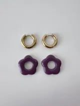 Aros de acero quirúrgico dorados con argollas pequeñas y dijes colgantes en forma de flor color celeste.