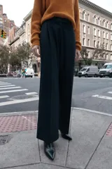 Pantalón de tiro alto color bordó, con pinzas delanteras, bolsillos frontales y falsos bolsillos con solapa en la espalda. Tiene pernera ancha y cierre frontal con cremallera, botón interior y gancho.