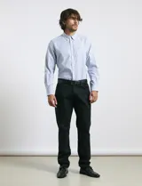 Camisa de corte clásico confeccionada en tejido oxford, con diseño de rayas verticales en tonos azul y blanco. Presenta cuello abotonado, cierre frontal con botones y bolsillo en el pecho con detalle de etiqueta bordada.