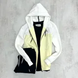 Campera con capucha blanca y cuerpo amarillo, con cierre frontal y bolsillos tipo canguro.