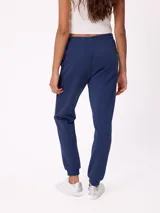 Pantalón tipo babucha de algodón y poliéster, con cintura elástica ajustable mediante cordón, bolsillos laterales y puños elásticos en los tobillos. Presenta un pequeño logo bordado en la pierna izquierda.