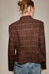 Blazer de cuello subido y manga larga, con diseño peplum en el bajo y cierre frontal con botones. Confeccionado en tejido texturizado a cuadros.