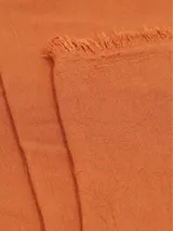 Bufanda lisa color naranja, con flecos pequeños en los extremos.