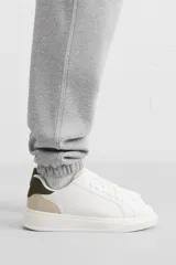 Zapatillas deportivas blancas con detalle de color gris en el talón y suela con volumen.