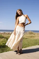 Falda larga de lino color crudo, con cintura cómoda y múltiples niveles de volados que aportan movimiento y fluidez.