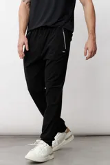 Pantalón deportivo de corte recto y ajuste holgado, color negro, con cintura elástica con cordón ajustable, bolsillos laterales con cierre y detalle de logo pequeño en el muslo.