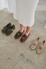 Mocasín estilo náutico de gamuza marrón, con cordones de cuero, borla decorativa y cuentas de colores en el empeine.