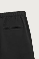 Pantalón jogger de corte regular fit y color negro, confeccionado en tejido compacto de algodón con interior de rizo. Cuenta con cintura elástica, bolsillos frontales y un bolsillo trasero de doble vivo.