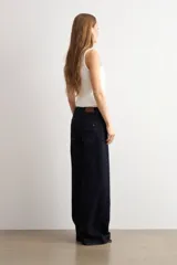 Pantalón de jean azul oscuro con corte flare, tiro alto y bolsillos delanteros tipo plaqué. Presenta costuras a la vista y una silueta amplia en las piernas.