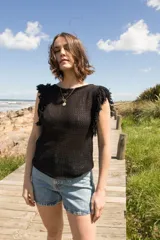 Musculosa tejida color violeta con diseño calado y flecos en los hombros.