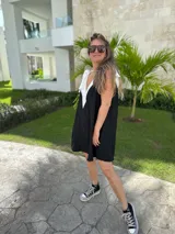 Vestido corto color beige, con escote en V con borde blanco, breteles anchos con lazos y corte holgado.