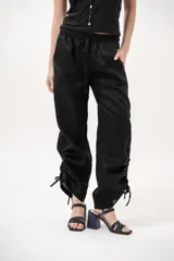Pantalón negro de tiro medio con cintura elástica ajustable con cordón y detalles de fruncido con tiras en los laterales de las piernas.