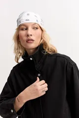 Campera de jean color negro, de calce amplio y largo a la cintura, con cuello alto y cierre frontal con broches a presión.