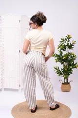 Pantalón de tiro alto y pierna ancha con estampado de rayas verticales en tonos blanco y beige, corte holgado y relajado.
