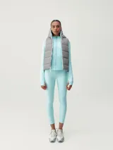 Chaleco acolchado reversible con capucha, cierre frontal de cremallera y bolsillos laterales. Diseño cortavientos y funcional con relleno vegano.